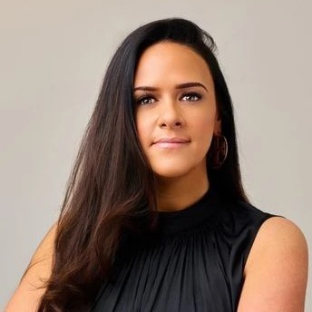 Brunette woman with dark eyes and a black dress, wearing large hoop earrings.