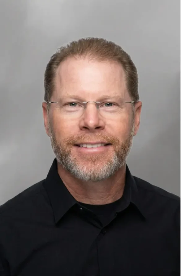 Man with glasses and beard wearing a black collared shirt