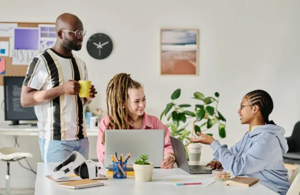 Diverse team collaborating at desks with laptops in modern office
