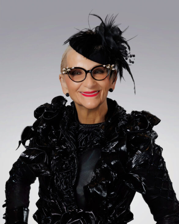 Stylish woman in black feathered hat and ornate cat eye glasses, wearing a black avant garde jacket