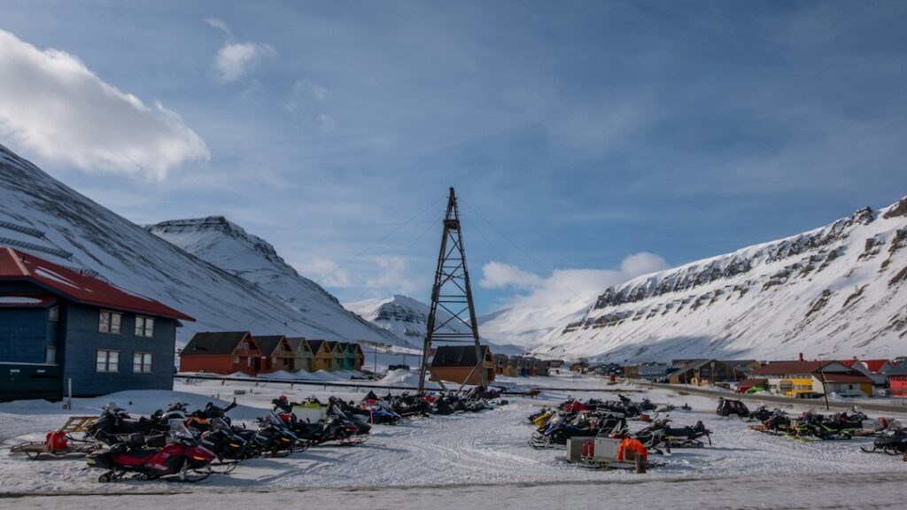 Snowy arctic town with colorful buildings and parked snowmobiles