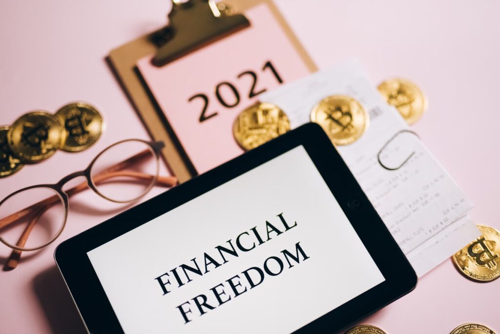 Tablet displaying 'Financial Freedom' surrounded by bitcoins and 2021 planner, symbolizing cryptocurrency potent...