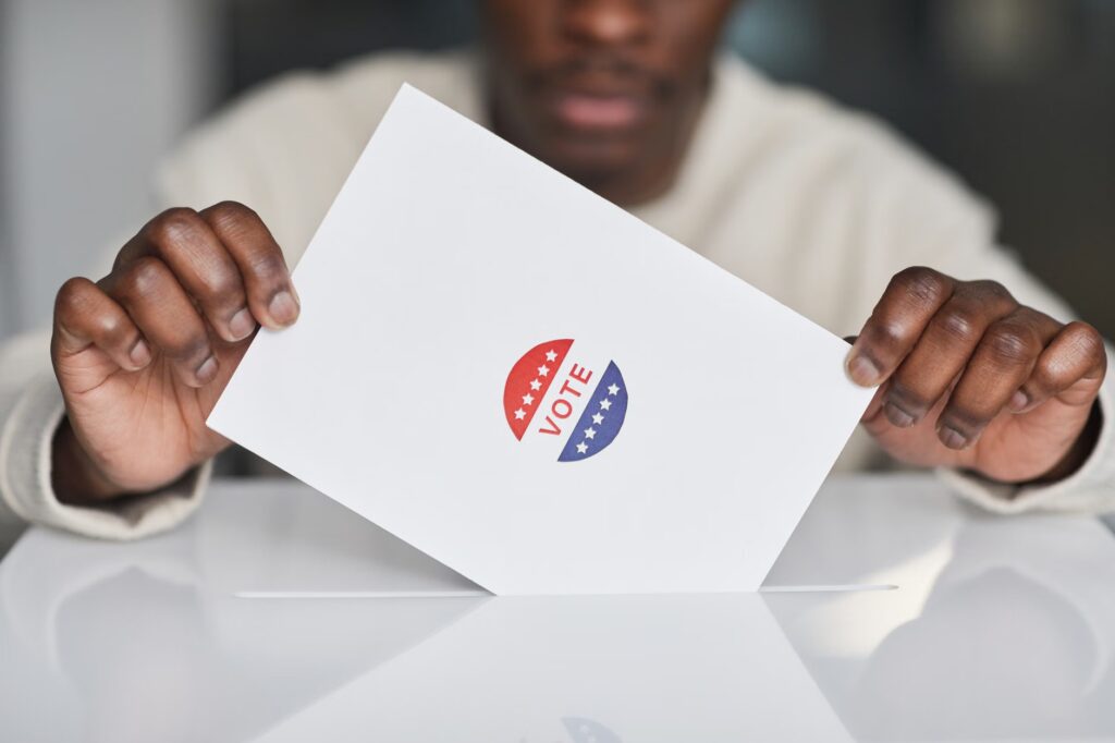 A voter placing a ballot into a box during an election. Focus on the act of voting.