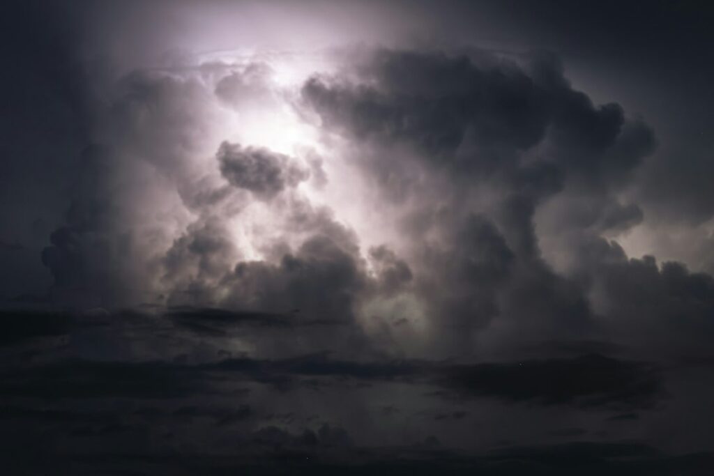 Bright lightning illuminating dark, dense storm clouds in the night sky