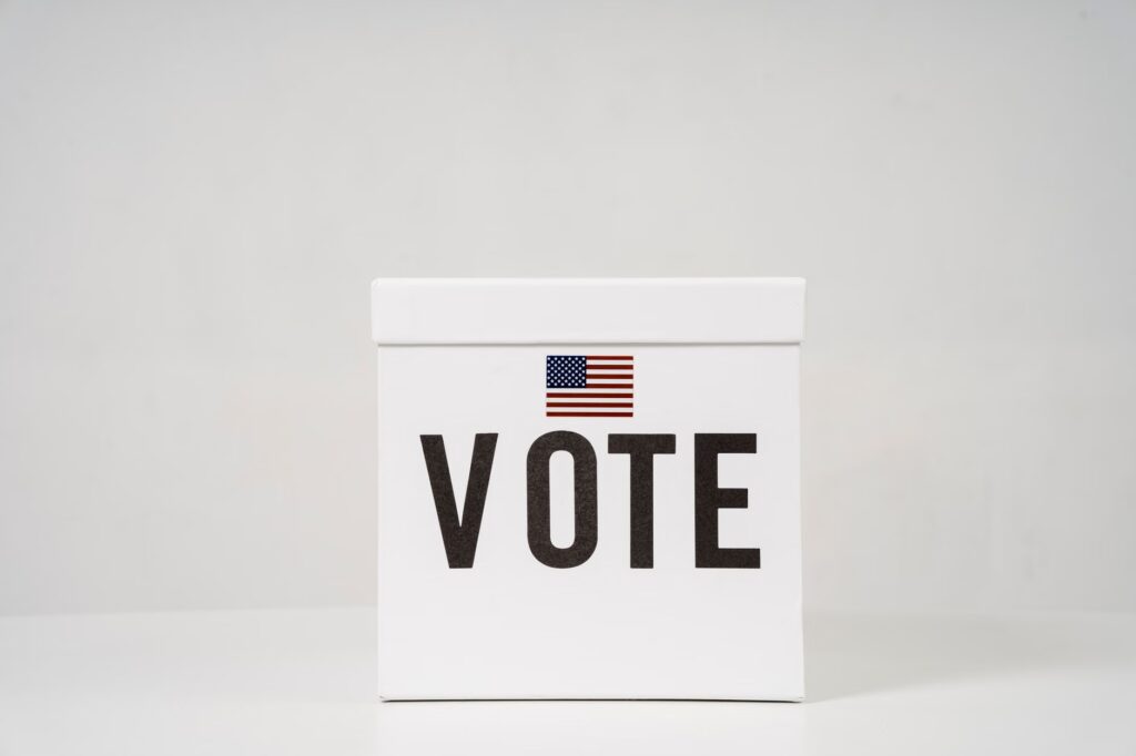 A minimalist ballot box with 'Vote' and an American flag, symbolizing elections.