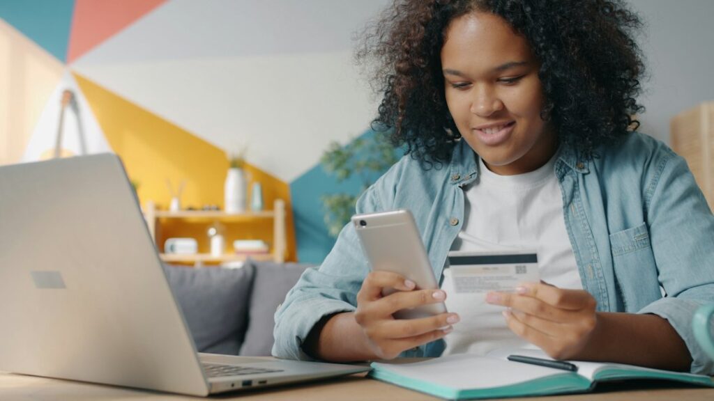 Teenager using phone and credit card for online shopping