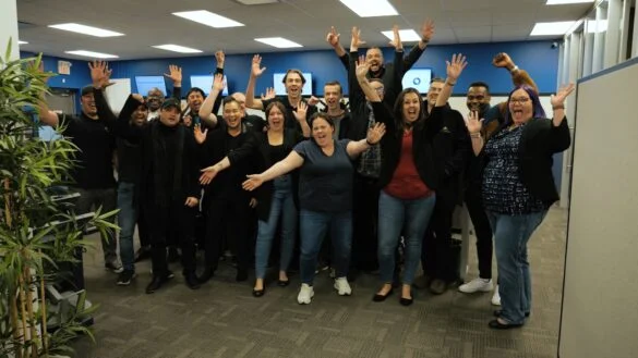 Diverse group of colleagues in office raising their hands in celebration