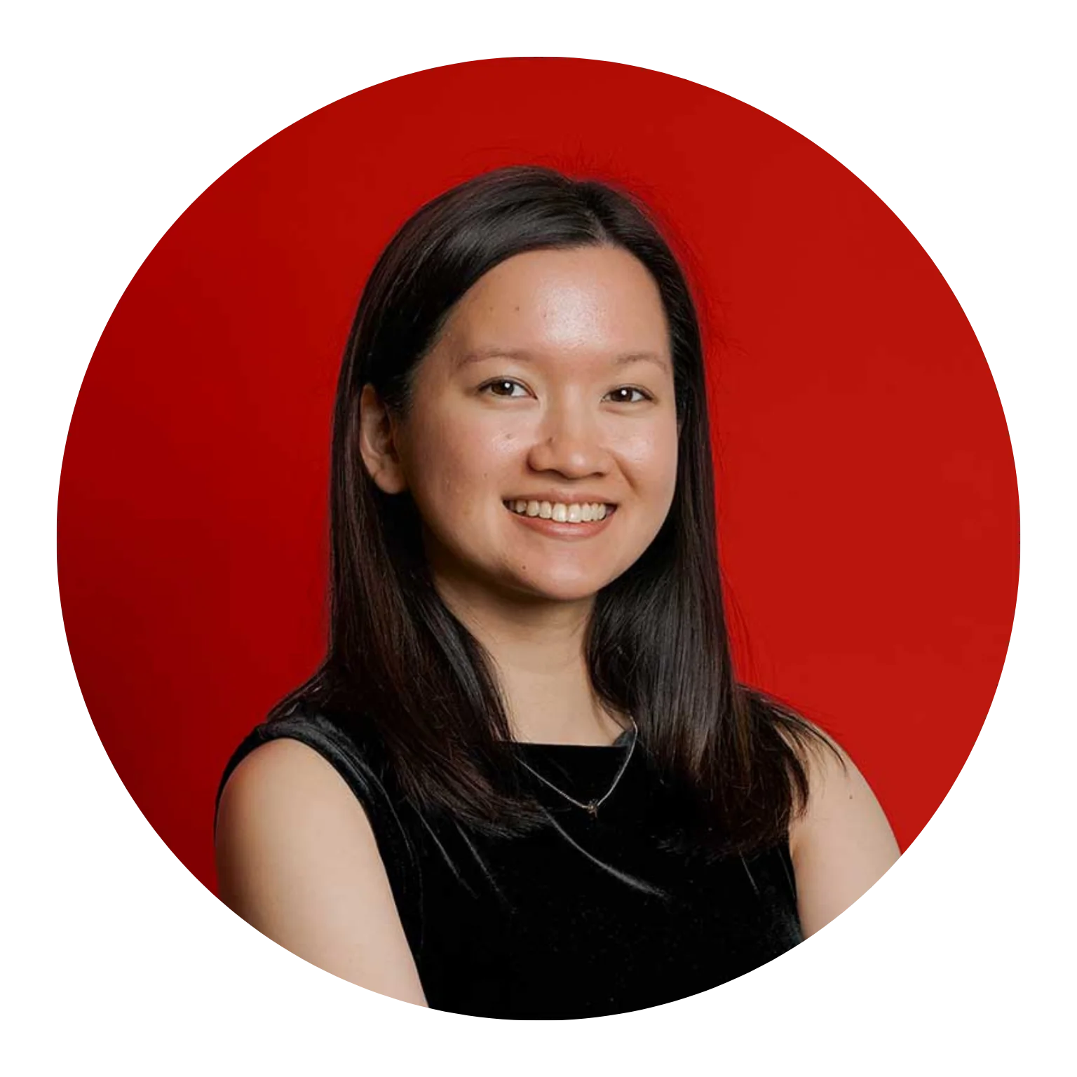Young woman with dark hair smiles in a black sleeveless top against a red background.