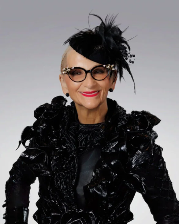 Stylish woman in black feathered hat and ornate cat eye glasses, wearing a black avant garde jacket